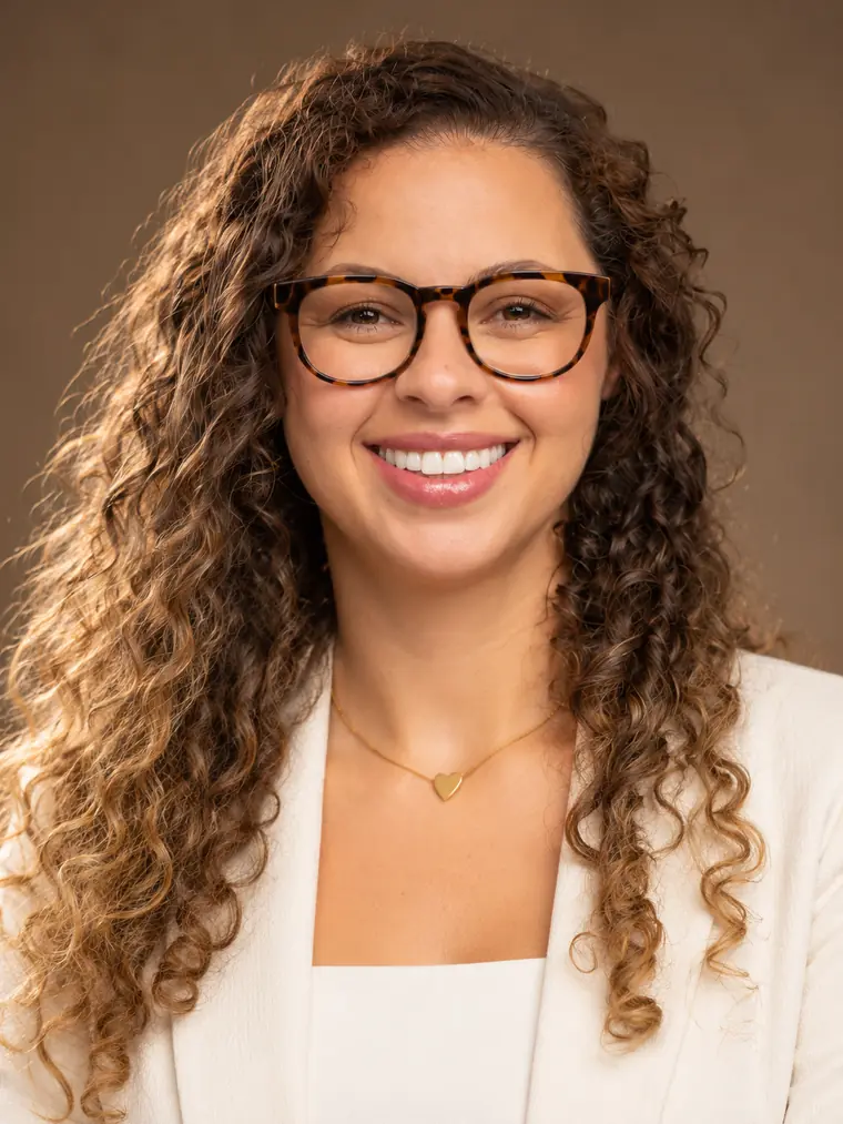 Ellen Cristine Vanali, advogada, de óculos e blazer branco, sorrindo